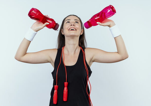 奶瓶戴着头巾的年轻健身女士拿着一瓶水 站在白色背景下 准备在锻炼后喝水抱着健身之后