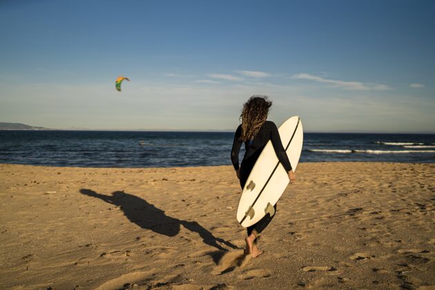 海岸线浅焦拍摄一名女性携带冲浪板 而在西班牙的海滨散步散步女孩健身