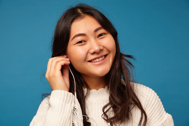 模特迷人的年轻积极的亚洲女性波浪式发型插入耳机年轻黑发休闲
