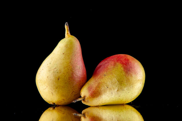 饮食正面是一个完整的成熟的黄色与红色的梨躺在黑色的背景与自由空间可食用水果梨水果