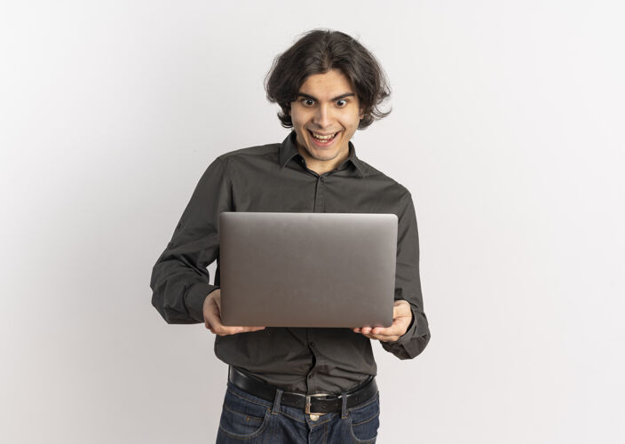 笔记本电脑年轻帅气的白人男子拿着一台笔记本电脑 看了看 这台笔记本电脑被隔离在白色的背景上 还有复印空间年轻惊喜拿着
