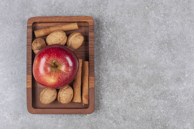 农业红苹果 核桃和肉桂棒放在木盘上顶视图新鲜复制空间