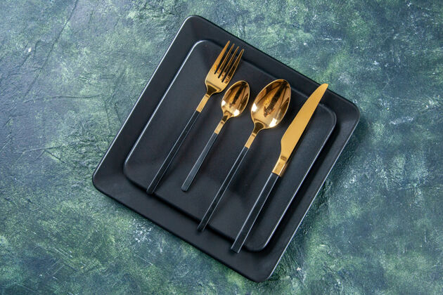 刀顶视图深色盘子上有金色的勺子刀叉在深蓝色的表面食物餐具颜色咖啡馆厨房餐厅黑暗颜色笔记本深色