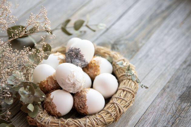 鸡蛋复活节静物与装饰复活节彩蛋和装饰巢在木制表面与干树枝传统巢穴构图