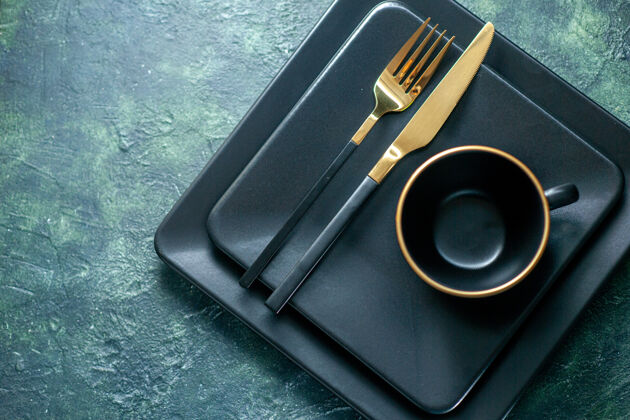 笔记本顶视图深色方形盘子 带金色叉刀和杯子 背景为深色餐具餐厅午餐色盘子茶饮料颜色顶部餐具