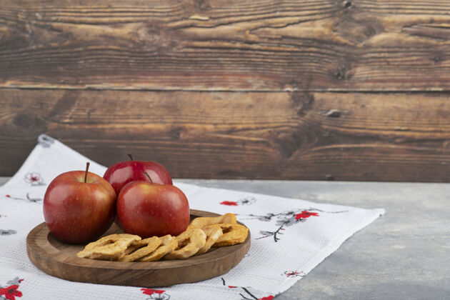 桌布在白色桌布上放着干苹果圈和红苹果的木盘水果食品红色