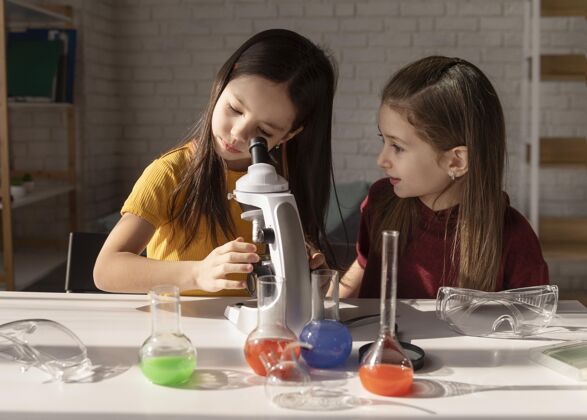 学习中镜头女孩透过显微镜看学习中镜头孩子