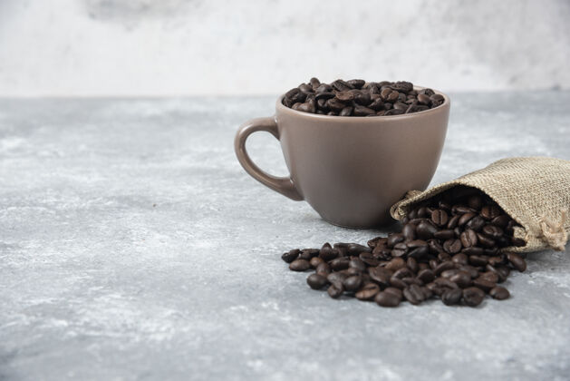 食物把咖啡豆从粗麻袋中取出 放在大理石上的杯子里豆类陶瓷粗麻布