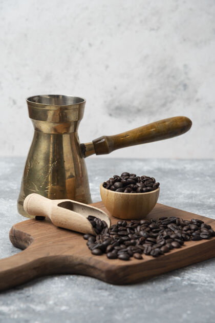 豆类黑烤咖啡豆和咖啡机放在木制砧板上粗麻布咖啡机
