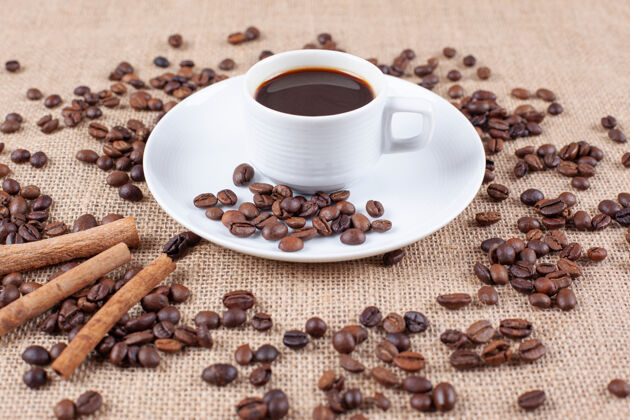 芳香一个有咖啡豆和肉桂棒的咖啡杯美味盘子蒸汽