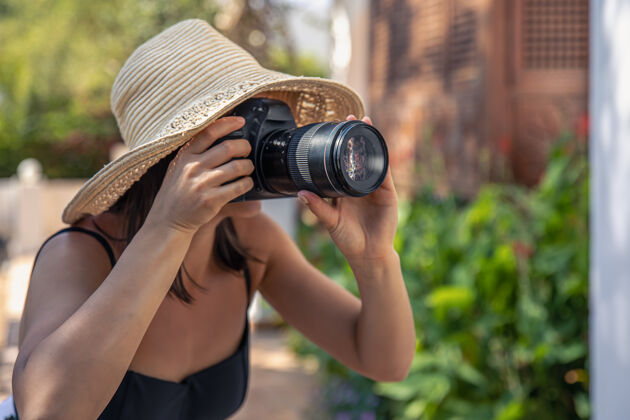 摄影师炎炎夏日 一位戴帽子的年轻女子用专业单反相机拍照爱好女人帽子