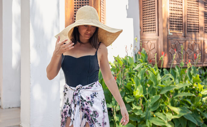 时尚在炎热的夏天 一个戴着大草帽的女孩站在一栋老房子的正面附近时尚乡村女人