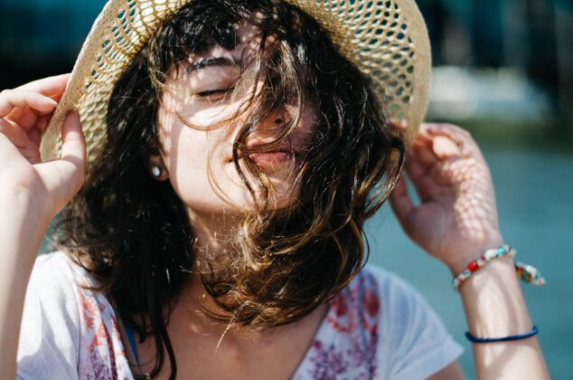 阳光浅焦拍摄的一个女人拿着她的帽子 而享受阳光明媚的一天 她闭上眼睛自然女性放松