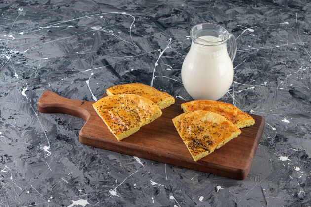 烘焙在大理石背景上放上一块木板 上面是新鲜的糕点片和一杯牛奶奶制品牛奶新鲜