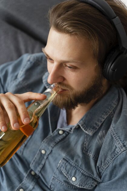 男性戴着耳机喝酒的男人在家室内生活方式