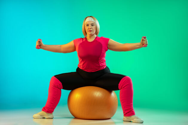 霓虹灯年轻的白人女模特在渐变绿的背景下训练健身房背景努力