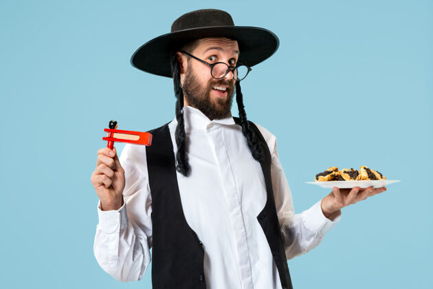 耳朵年轻的东正教犹太男子与哈曼塔森饼干节日普瑞姆节日 庆祝 犹太教 糕点 传统 饼干 宗教概念自制甜点种子