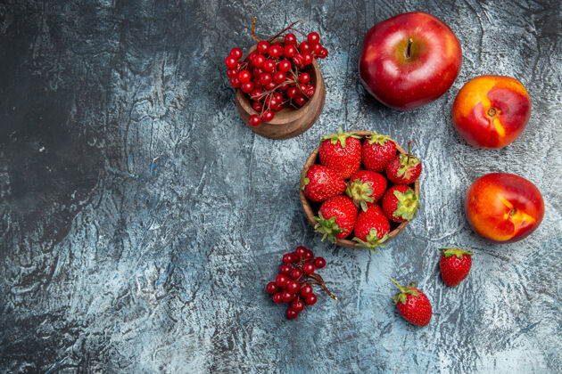多汁新鲜的红色草莓与桃子和苹果在黑暗的表面俯视图苹果饮食食品