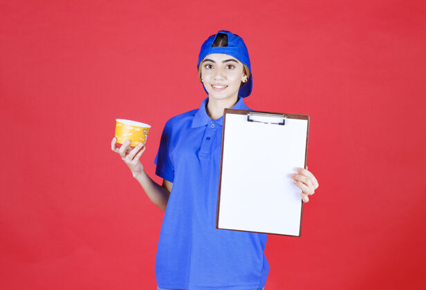 过程身穿蓝色制服的女信使手持黄色面杯 出示任务单供签字年轻人聪明空白