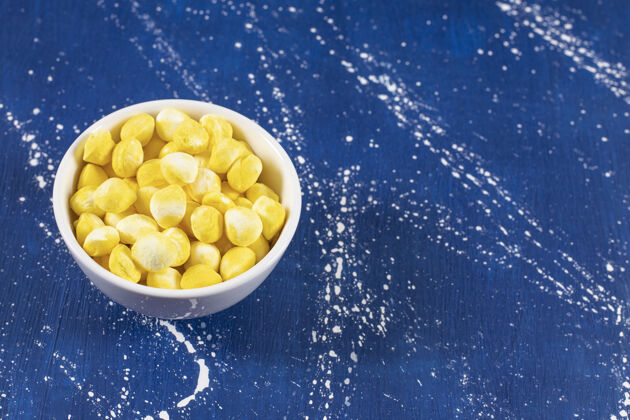 糖果白色的碗里装满了黄色的硬糖 蓝色的硬的甜点黄色