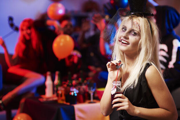 派对用一杯血腥的饮料接近这位年轻女子服装万圣节女人