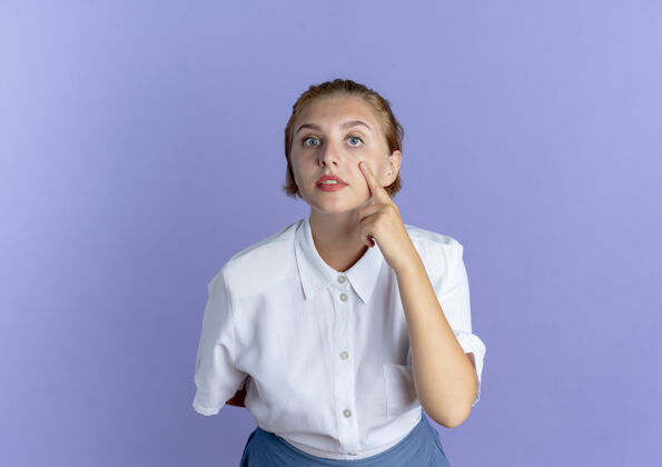 俄罗斯年轻自信的俄罗斯金发女孩指着紫色背景上孤立的眼睛复制空间眼睛金发自信