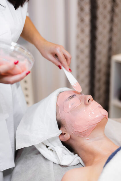 服务美容师用抹刀在女人脸上敷海藻酸钠面膜谎言护理女性