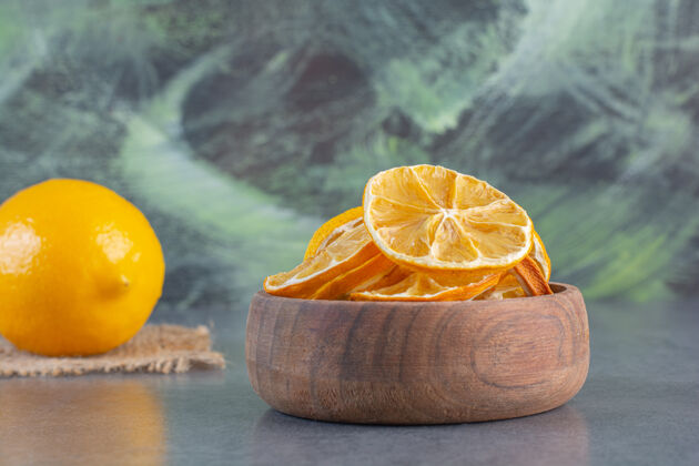 圆形一碗柠檬片和整个柠檬放在石头背景上整个柑橘生的