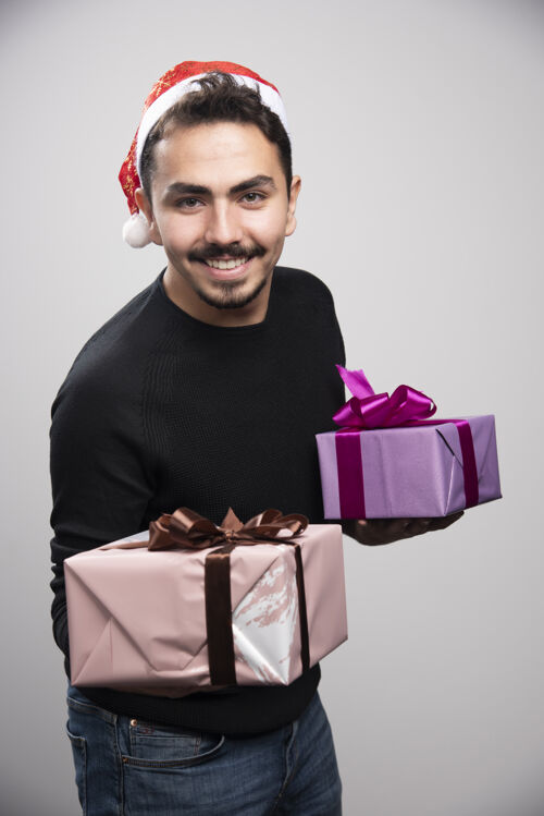 圣诞老人一个年轻人拿着礼品盒在灰色的墙上盒子男人圣诞