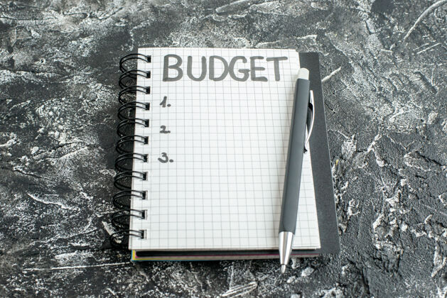 笔记本前视图预算写在记事本上的笔记与灰色背景上的笔活页夹抄写本大学