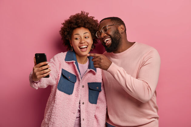 拍照快乐无忧无虑的黑皮肤千禧一代情侣在现代手机上自拍 男人笑着指着展品 自拍朋友非洲卷发