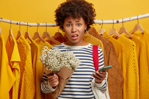 担心不高兴的黑皮肤女人在时装店对着衣架摆姿势 网上付款有问题惊奇衣柜时尚