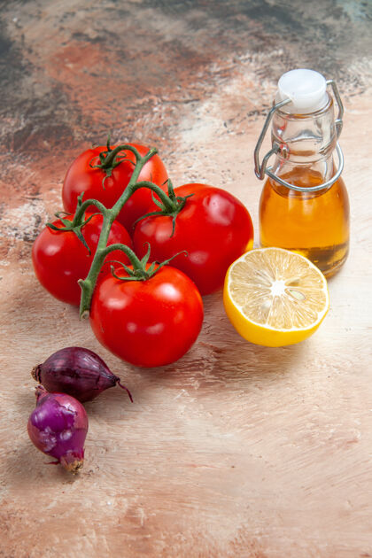 素食侧面特写西红柿一瓶油西红柿洋葱柠檬放在桌子上壁板蔬菜食物