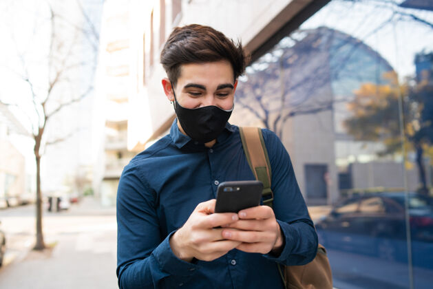 男人年轻人在街上户外散步时使用手机的照片新的正常生活方式概念城市概念手机保护肖像