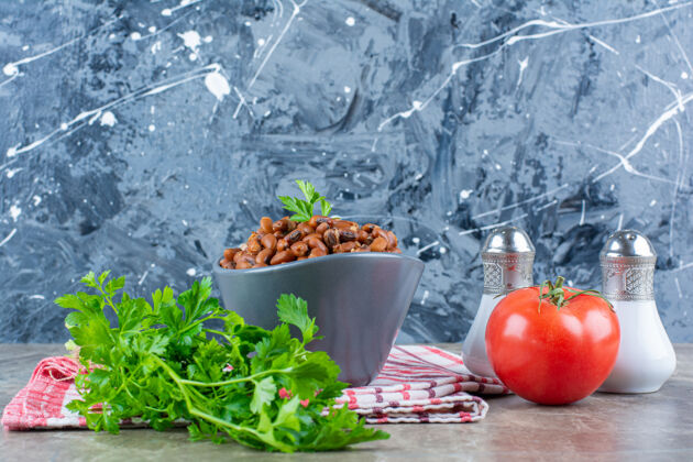 桌布一碗煮熟的豆子和新鲜的红西红柿配欧芹放在桌布上红色新鲜盐