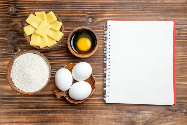糕点俯视整个生鸡蛋与面粉和奶酪在棕色木制桌子上鸡蛋面团面粉粉粉面粉奶酪鲍勃