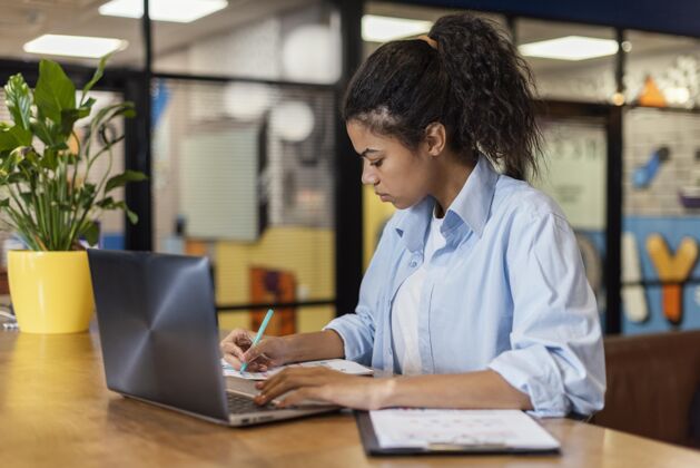 笔记本电脑女士在办公室里用笔记本电脑工作的侧视图女性职业水平