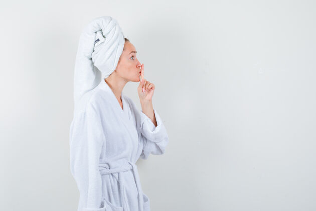 女孩年轻女子在白色浴衣 毛巾和显示沉默的姿态仔细看 前视图健康女士手势