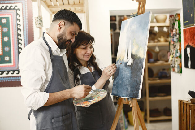 女性一对成年夫妇在艺术工作室里的爱情故事他们画画 大笑 亲吻他们的情感 感情 爱男人混合画架