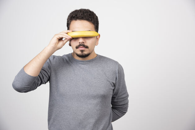 健康食品一个年轻人用香蕉遮住眼睛表情黄色男性