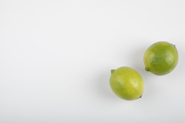 自然两个成熟的酸橙果实 白色背景绿色平铺新鲜