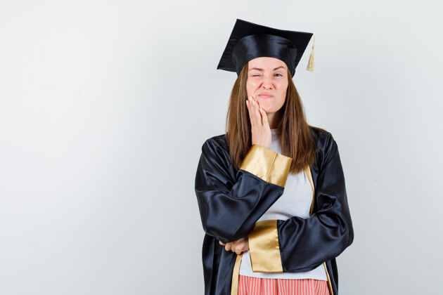 证书毕业的女人手拉着下巴 穿着休闲服 穿着制服 神情沉思前视图成人帽子人民