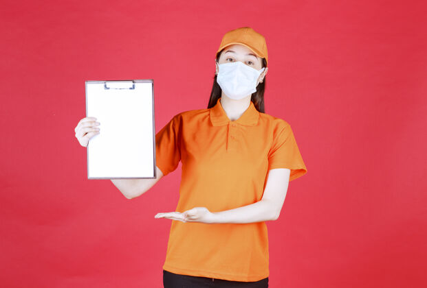 面具身着橙色制服和面具的女服务人员展示项目表并指着它报告演示简介