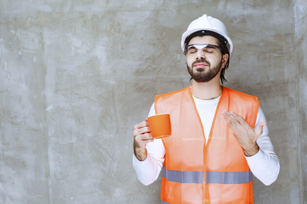 味道戴着白色头盔拿着橙色杯子的工程师工作场所成人质量