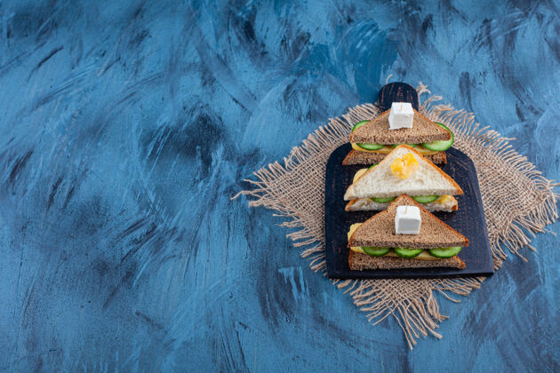 酵母把三明治放在裁板上 放在粗麻布餐巾上 放在蓝色的桌子上美味奶酪砧板