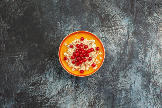 浆果上图：灰色桌子上橙色盘子上的美味红醋栗顶部柑橘餐