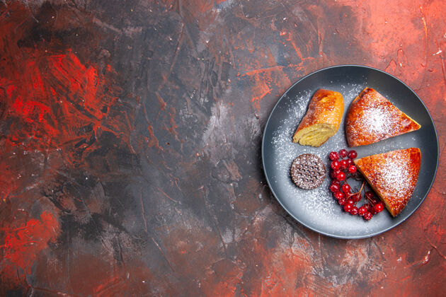 美食俯瞰美味的切片派与红色浆果在黑暗的桌子上馅饼甜蛋糕烧烤热鱼