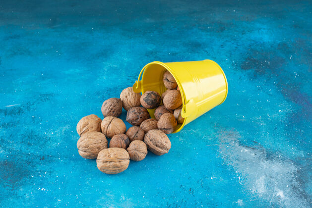 坚果把核桃壳放在蓝色的桶里美味天然木桶