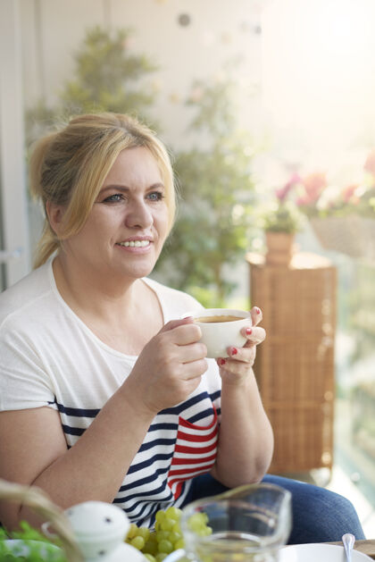 早餐阳台上喝咖啡的女人的特写照片饮用咖啡咖啡杯