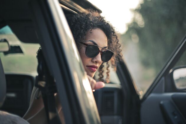 姿势卷发戴墨镜的女人从车里往外看头性感太阳镜